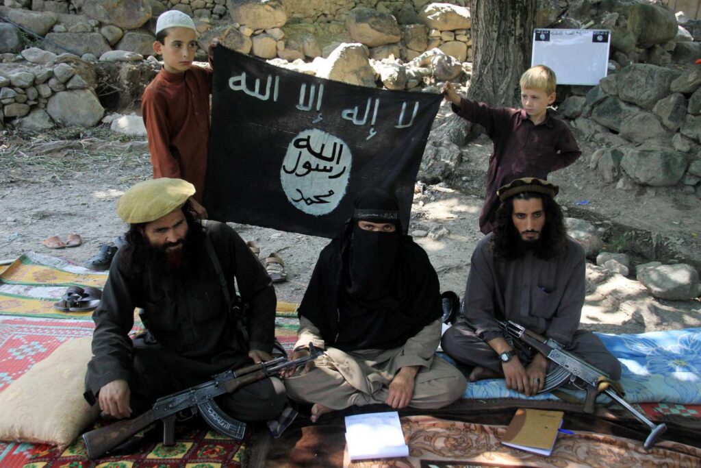 Miliziani armati con bandiera ISIS durante un raduno jihadista in zona di conflitto