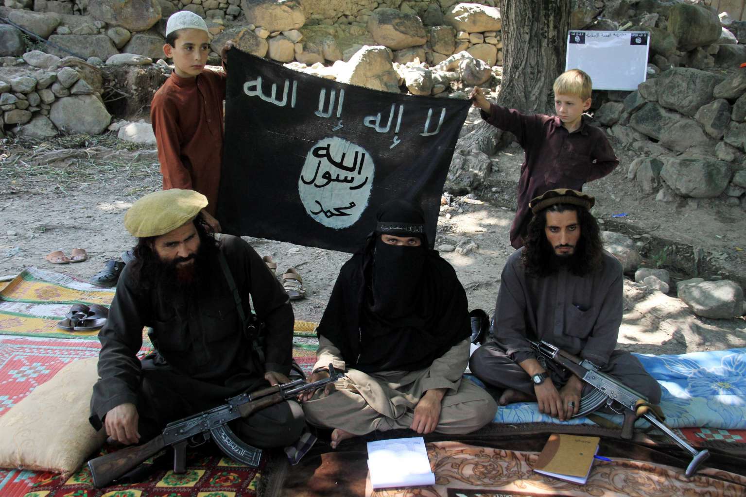 Miliziani armati con bandiera ISIS durante un raduno jihadista in zona di conflitto